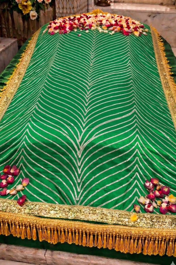 Green and gold draped table with floral arrangements on a stone surface


