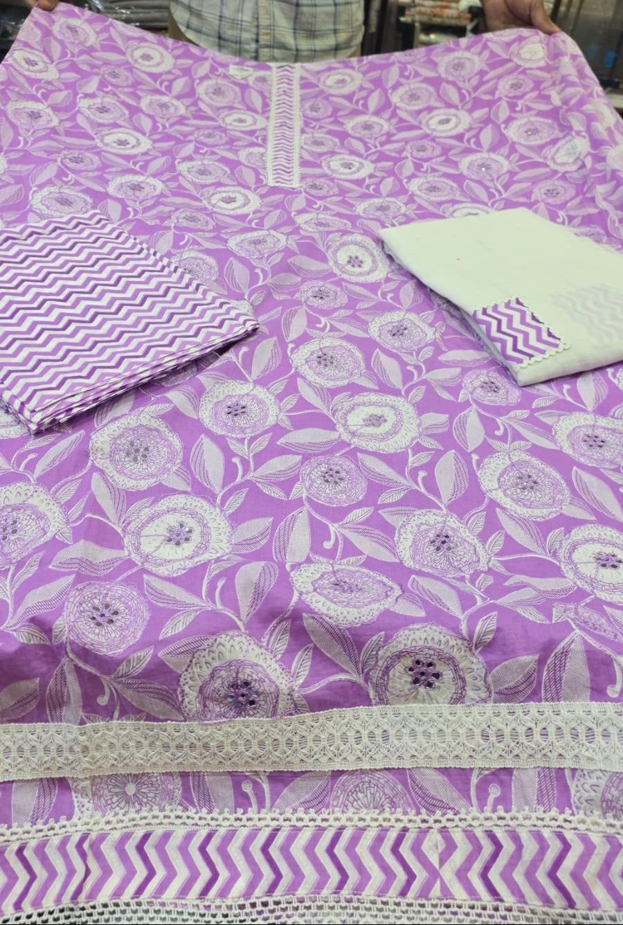 Purple fabric with white floral patterns displayed on a table.